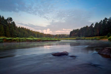 The nature of Russia. Tvertsa River in the early morning, fog creeps along the banks covered with...