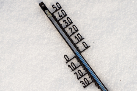 Thermometer on snow shows low temperatures in degrees Celsiusの写真素材