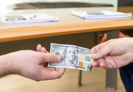Man offering of hundred dollar bill. Hands close up. Corruption concept.  United States Dollars (or...