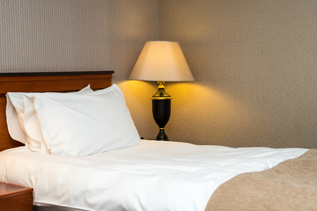 two pillows on bed and lamp on wooden table in hotel roomの写真素材