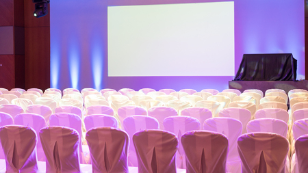 Empty interior of luxury conference hall or seminar room with projector screen and white chairsの写真素材
