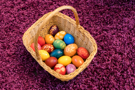 Colorful Easter eggs in basket on purple backgroundの写真素材