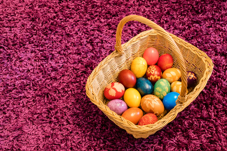 Easter eggs in basket on purple carpet backgroundの写真素材