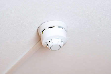 Smoke detector of fire alarm on white ceiling.の写真素材