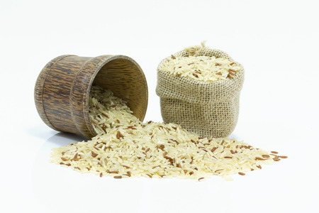 Rice in burlap sack and wood bowl on white backgroundの写真素材