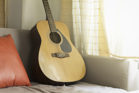 Classic Guitar with red pillow on sofa. Chill music concept