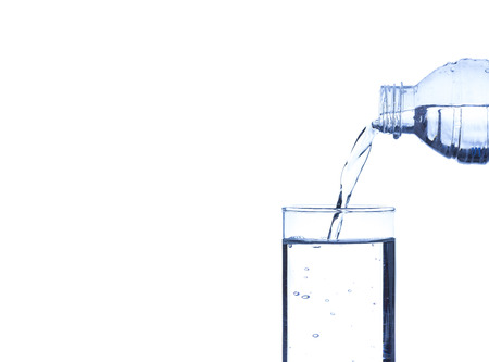 Concept of drinking. Pouring water from into glass on white background with blank areaの写真素材