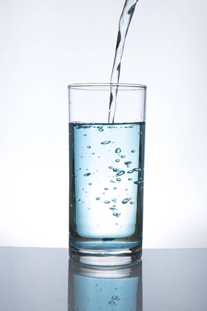 Concept of drinking. Pouring water from into glassの写真素材