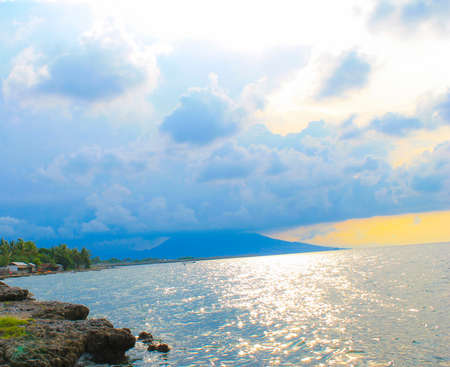 Indonesia beach with beautiful tropical landscape, have a rock, tree, mountain, blue sky and clear ocean waterの写真素材