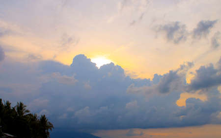 sunset in indonesia, there is a cloudy sky and trees in the cornerの写真素材