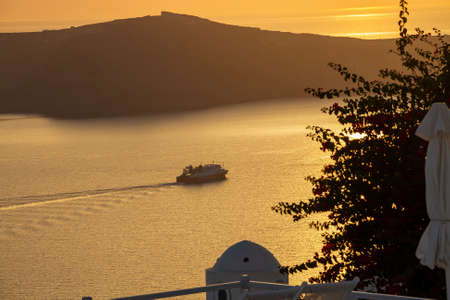 Boat, sea, orange sky, sunset time, dusk in Santorini island, Greece