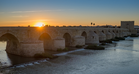 The incredible Roman bridge over the River Guadalquivir at the ancient moorish town of Cordoba at sunset, with the sun dipping behind the bridgeの写真素材
