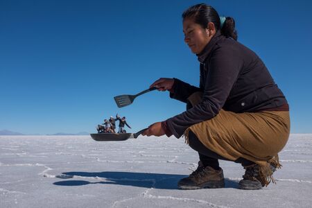 Uyuni, Bolivia, June, 11, 2015: A great weird prospective shot at Salar de Uyuni as this cook looks like she has tourists in her frying pan, Salt Flats, Bolivia against a bright blue skyのeditorial素材
