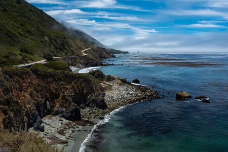 The rugged coastline of Big Sur, CA with the highway weaving and hugging the hills overlooking the...