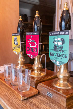 Lyme Regis, Dorset, England, February, 24, 2019: Beer pumps inside the Lyme Regis Craft Brewery, with empty sampler glasses in the foregroundのeditorial素材