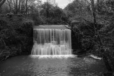 Trully Waterfall just outside the village of Trully in Somerset shot in black and white and from a footbridgeの写真素材