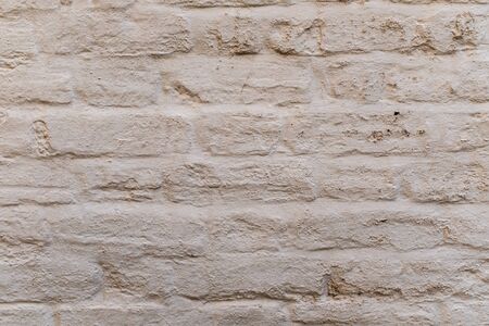 A close up of a white washed brick wall highlights the details of the bricks, ideal as a background or wallpaperの写真素材
