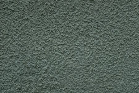A close up photo of an exterior wall painted green textured, surface with stucco daub, great for background imagesの写真素材