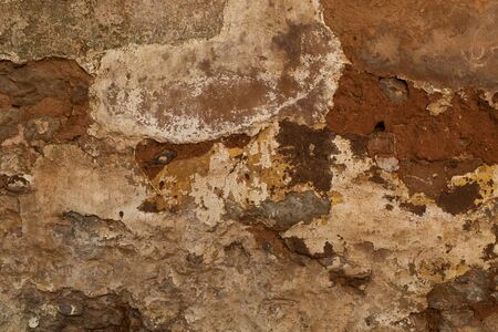 Close up of layers of various colours of plaster crack away from a brink wall, great for wallpaper or backgroundの写真素材
