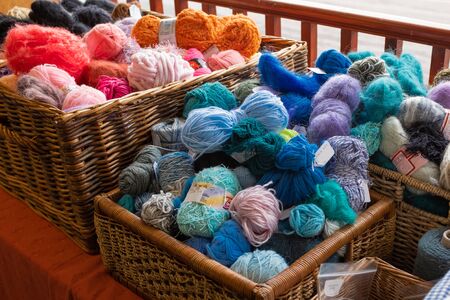 A close up of several  wicker baskets of knitting wool for sale, mostly blues and orangesの写真素材