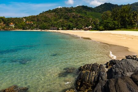A beautiful small cove beach on the island of Koh Lanta, Thailand with the sparkling waters of the Andanman Sea with rocks in the foreground, nobody in the imageの写真素材