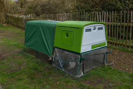 A three quarter shot of a green modern bright looking chicken coup or hen house with covered topの写真素材