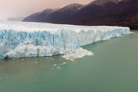 The the face of the Perito Moreno Glacier located in the Los Glaciares National Park in Santa Cruz Province, Argentina. With the autumn tree colours in the foregroundの写真素材