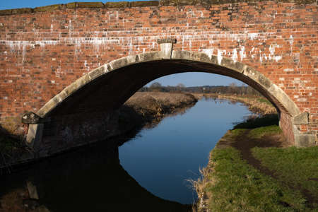 The towpath of the Chesterfield canal leading to a bridge on a bright sunny day
