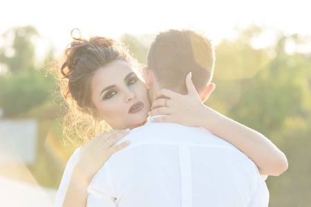 Young woman hugging her boyfriend. Back light and lens flareの写真素材
