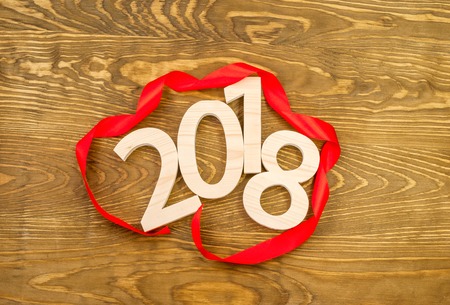 New Year's concept. Figures 2018 carved from wood on the background of a polished board framing a red ribbonの写真素材