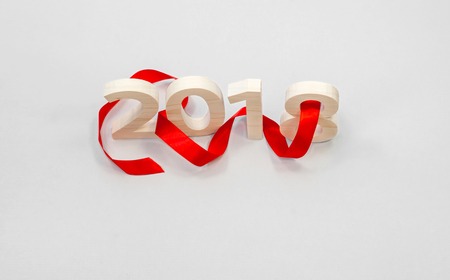 Wooden figures forming 2018, carved from light wood on a gray background with a red ribbon. New Year Idea, postcard, poster, greetings. Festive decor.の写真素材