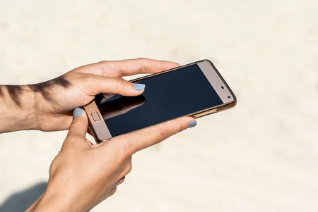 hand of a girl holds a mobile phone with a black screen. Empty space for promotional messageの写真素材