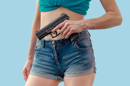 Girl holds a black pistol in her hand.