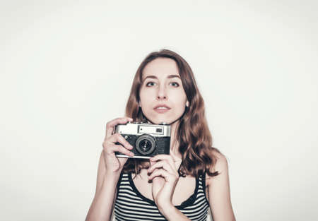 Nice girl in a striped t-shirt with vintage camera in her hands. Photographing people.の写真素材