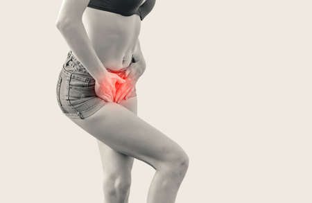 Young woman in shorts and a bra is experiencing pain in the uterus, pressed her hands to the lower...