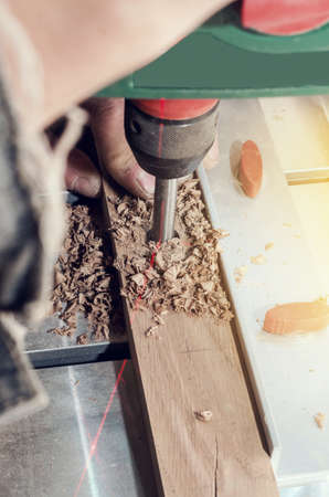 Drill mill for tree in the boring machine with a laser marking. Hands master drills a hole in a wooden bar.の写真素材