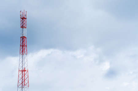 Mobile telecommunication tower with communication antennas in the background of dense clouds