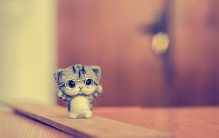 Felting toy little gray kitten in glasses on wooden standの写真素材