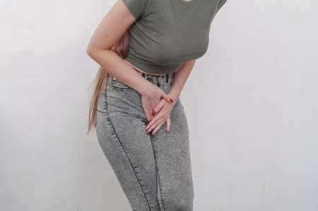 Young slim girl in jeans holds hands pressed between her legs. Women's health, gynecology