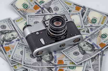 Vintage film camera on scattered American dollars. Concept of earning on photo stocks.の写真素材