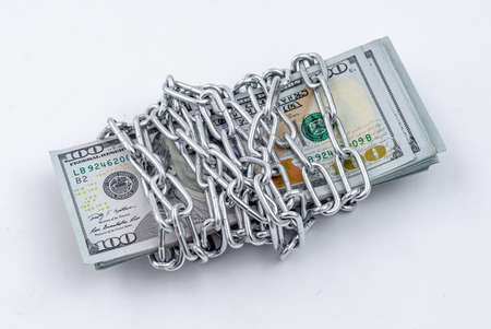 Bundle of American dollars rewound with a metal shiny chain. Isolate on white background.の写真素材