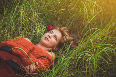 Woman laying on green grass with loose hair with applesの写真素材
