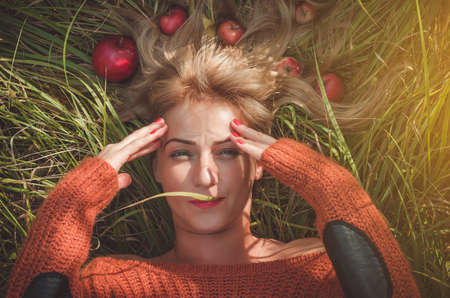 Woman laying on green grass with loose hair with applesの写真素材