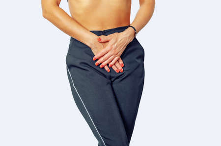 Woman is experiencing pain, discomfort in lower abdomen, uterus, urethra. Presses hands to stomach. Isolated on white background.の写真素材