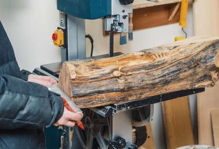 Hands joiner cuts a log on band saw. Woodworking, wood products, work, employment