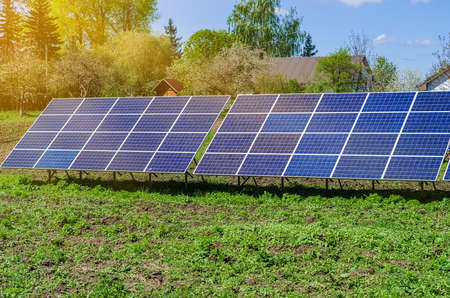 Photovoltaic ecological modules on green grass valley against of sun and cloudy sky.