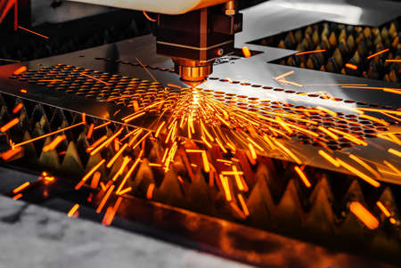 Machine for laser cutting of metal. Laser head cuts the sheet with a beam, sparks scatter in different directionsの写真素材