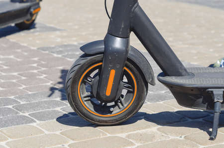 Electric scooter parked on cobblestones in city center. Moving around the city on scooter. Wheel close upの写真素材