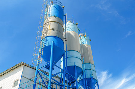 Large blue industrial tanks for cement, sand, water. Metal stairs leading to metal containers. side viewの写真素材