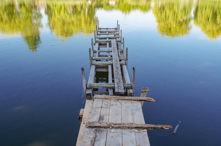 wooden old ruined bridge pier on small lake. Rest, fishing, rest on the waterの写真素材